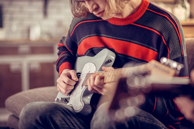 Guitarra nueva. Joven estudiante creativo sosteniendo su nueva guitarra y componiendo una bonita melodía