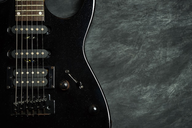 Guitarra preta no chão de cimento preto.