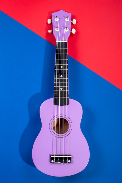 Guitarra ukelele de cuatro cuerdas sobre fondo azulado