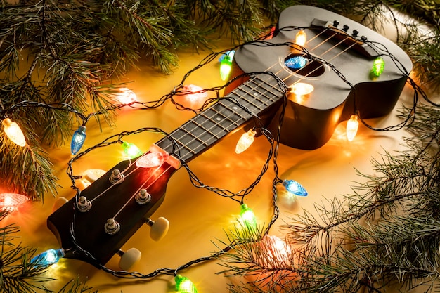 Guitarra ukulele com guirlanda iluminada em fundo escuro Formas clássicas de guitarra de presente para o Natal ano novo