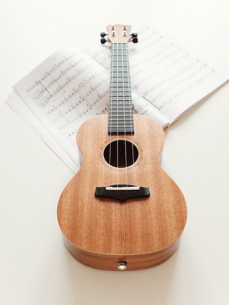 Guitarra ukulele marrón, partituras.