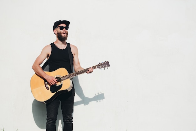 Guitarrista cantando lá fora. guitarrista hipster com barba e roupas pretas