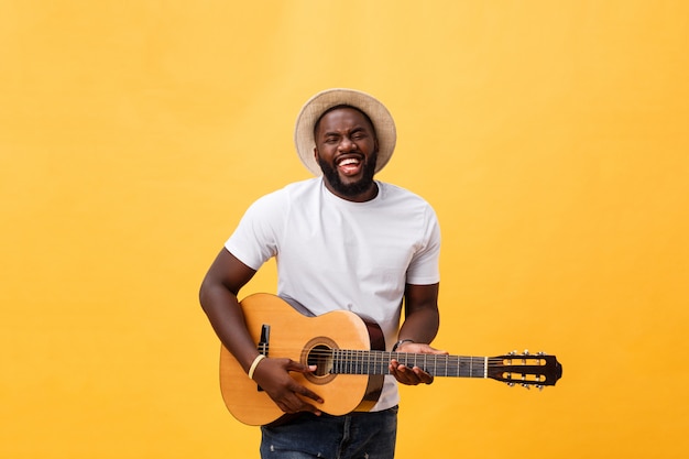 Guitarrista denominado retro afro-americano que joga a guitarra acústica isolada no fundo amarelo.