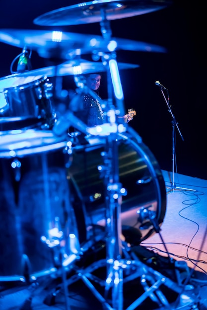 Guitarrista bajo detrás de la batería en un concierto en luz azul