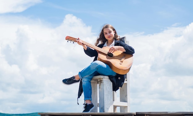 Guitarrista entreteniendo a los invitados en la fiesta pequeño amante de la música contenido de música gratis Músico adolescente tocando la guitarra Retrato de niño pequeño tocando la guitarra en el fondo del cielo lista de reproducción romántica de verano