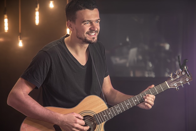 Guitarrista feliz em uma camiseta preta tocando violão em um show