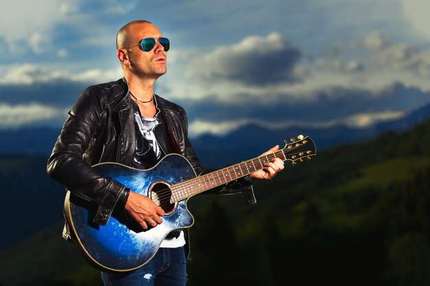 Guitarrista con guitarra acústica azul toca en la naturaleza