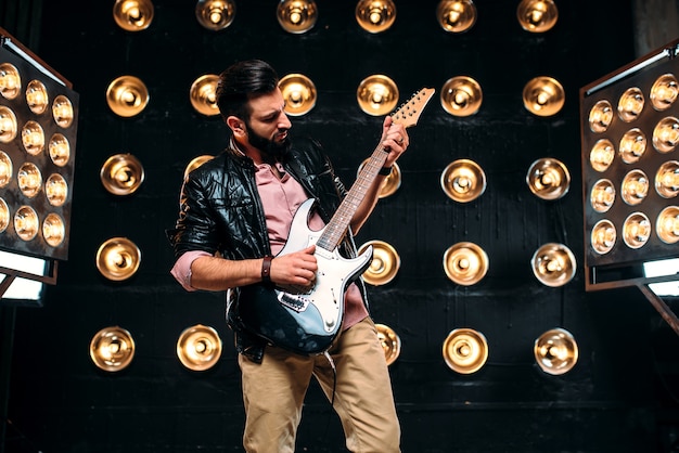 Guitarrista masculino no palco com decorações de luzes