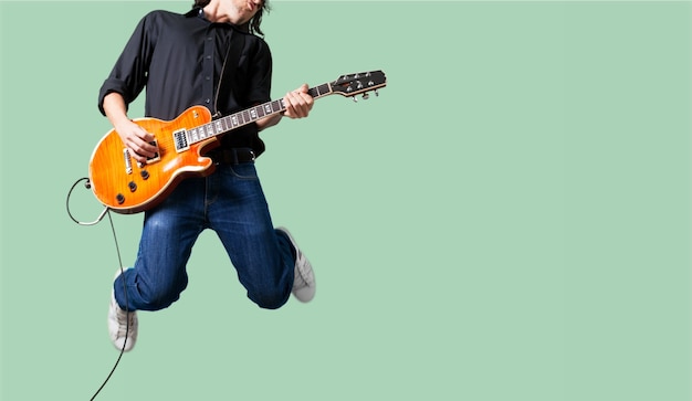 Guitarrista masculino tocando música en la pared gris