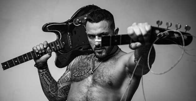 Guitarrista no show de rock abs sexy de homem de tatuagem segura eletro guitarra quebrada esporte e fitness br