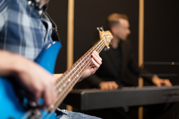 Foto guitarrista con pianista en el fondo