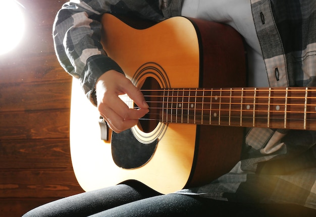 El guitarrista toca la guitarra sobre fondo de madera de cerca