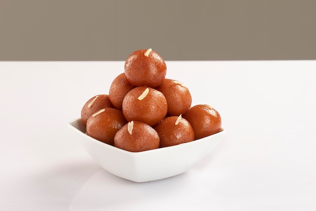 Gulab jamun con almendra servido en un cuenco blanco aislado en un fondo blanco