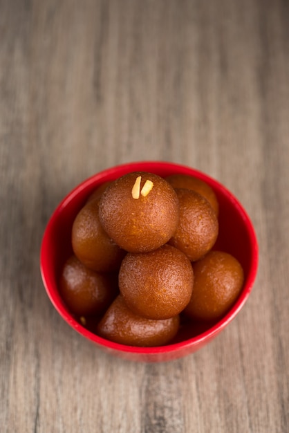 Gulab Jamun in roter Schale auf Holz