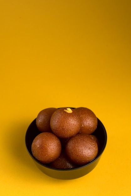 Gulab Jamun in Schüssel auf gelb.