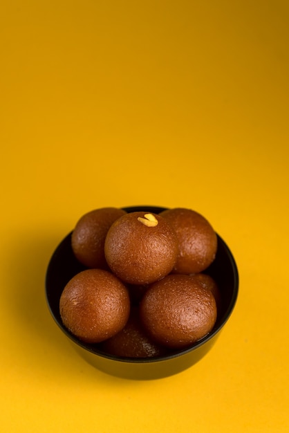 Gulab Jamun in Schüssel auf gelb.