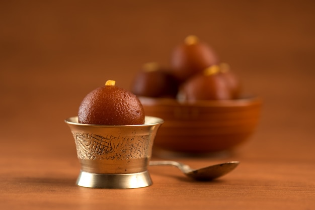 Gulab Jamun in Schüssel und Kupfer antike Schüssel mit Löffel. Indisches Dessert oder süßes Gericht.