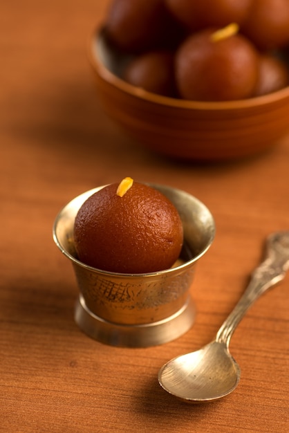 Gulab Jamun in Schüssel und Kupfer antike Schüssel mit Löffel. Indisches Dessert oder süßes Gericht.