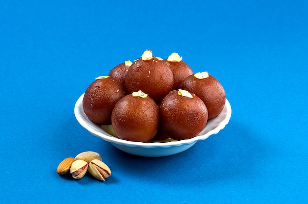 Gulab Jamun, postre indio con friut seco en tazón blanco con servilleta