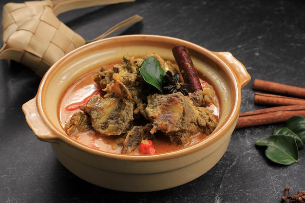 GULAI SAPI Gulai Sapi es curry de carne de res, comida típicamente tradicional de Padang, West Sumatera, Indonesia. Servido en la Mesa con Bowl y Ketupat Lebaran. Menú para Eid al Adha (Idul Adha)