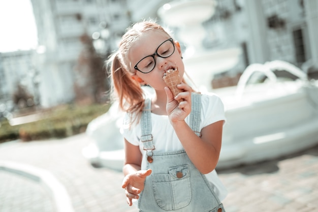 Guloso. menina concentrada apreciando seu sorvete comendo fechando os olhos no verão.