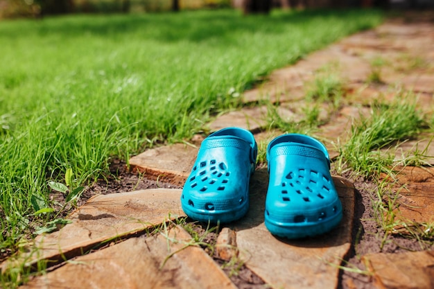 Gummisandalen stehen auf dem Gartenweg in der Nähe des Rasengrases