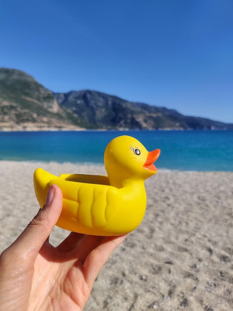 Gummispielzeug gelbe Ente in der Hand mit Blick auf das Meer