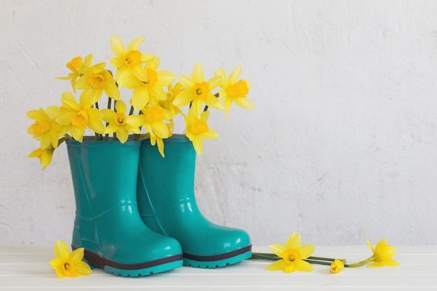 Gummistiefel und Frühlingsblumen auf weißem Hintergrund