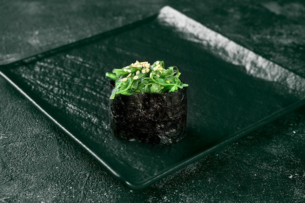 Foto gunkan maki sushi con algas hiyashi sobre una pizarra con jengibre y wasabi. cocina japonesa. entrega de comida. fondo negro