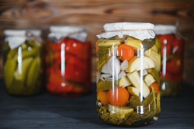 Gurken und Tomaten in Dosen mit Handwerk Deckel auf einem hölzernen Hintergrund Gurken und Tomaten mit Platz für Text Bestände an Konserven Ernte Bestände für den Winter