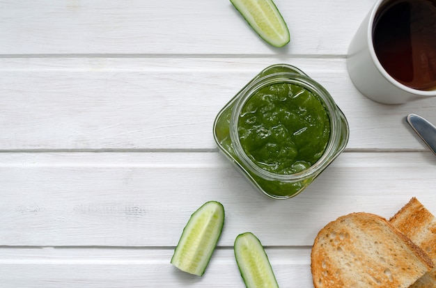 Gurkenmarmelade mit Gurkenscheiben und Ingwer mit Toast auf einem hellen hölzernen Hintergrund. Konzept für gesunde Ernährung.