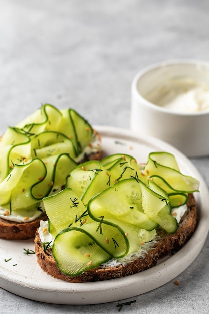 Gurkensandwiches mit Weichkäse schließen oben für köstliches gesundes vegetarisches Frühstück auf grauem Hintergrund mit Textraum