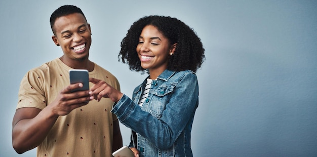 Se gustan de nuevo Foto de estudio de un hombre y una mujer jóvenes usando un teléfono móvil juntos contra un fondo gris