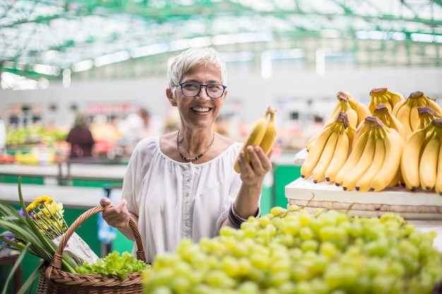 Gut aussehende ältere Frau kauft Bananen am Markt