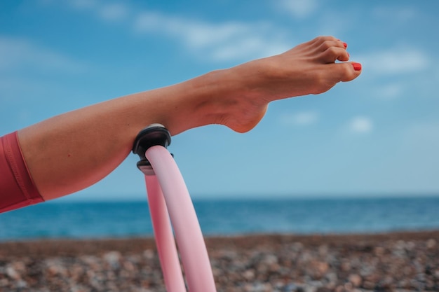 Gut aussehende Frau mittleren Alters mit schwarzem Haar, die Pilates mit dem Ring auf der Yogamatte in der Nähe macht