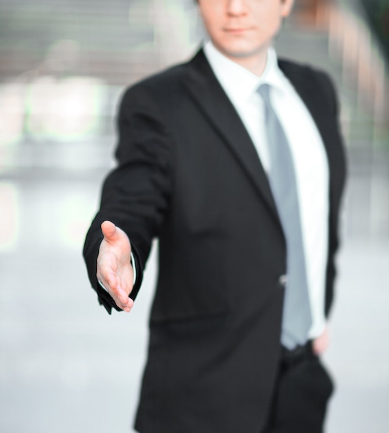 Gut aussehender Geschäftsmann, der die Hand für einen Handschlag ausstreckt. Das Konzept der Partnerschaft