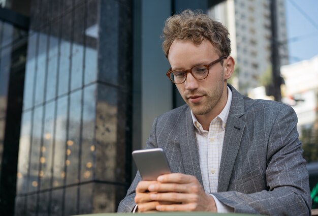 Gut aussehender Geschäftsmann, der mit Handy-Textnachrichten-Community arbeitet, die online Nachrichten liest