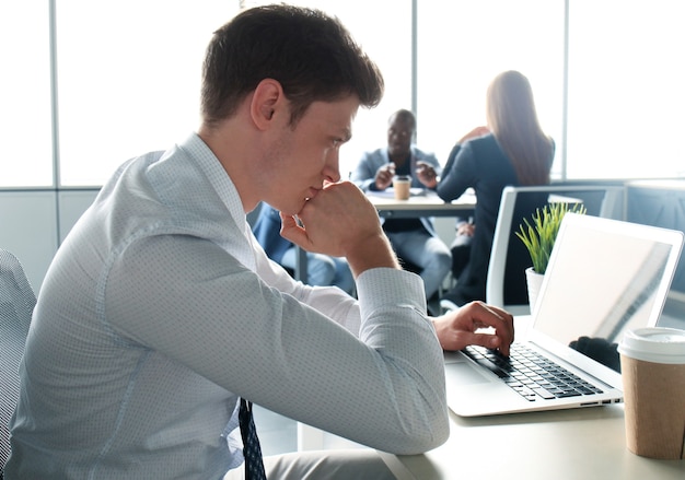 Gut aussehender Geschäftsmann, der mit Laptop im Büro arbeitet