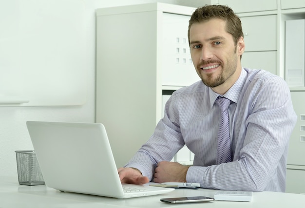 Gut aussehender Geschäftsmann, der mit Laptop im Büro arbeitet