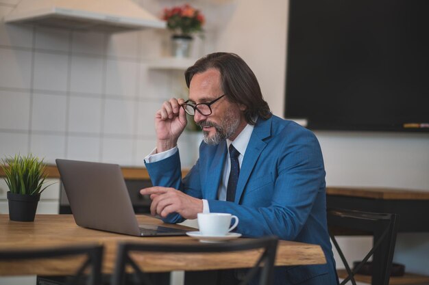 Gut aussehender intelligenter Mann mit Brille, der am Laptop arbeitet