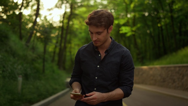 Gut aussehender Mann, der das Telefon im Freien aus der Tasche nimmt Guy SMS-Nachricht im Park