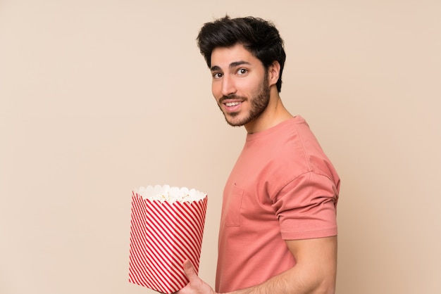 Gut aussehender Mann, der eine Schüssel Popcorn hält