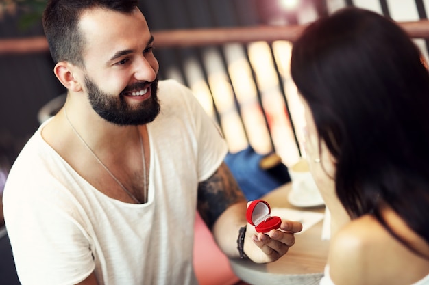 gut aussehender Mann, der einer schönen Frau im Café einen Vorschlag macht