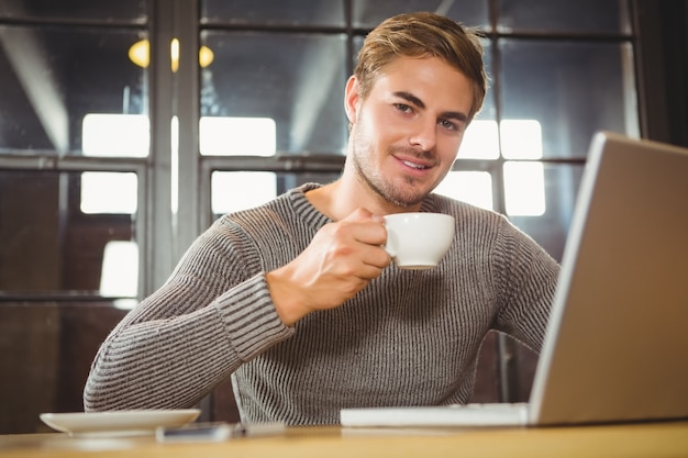 Gut aussehender Mann, der Kaffee lächelt und trinkt