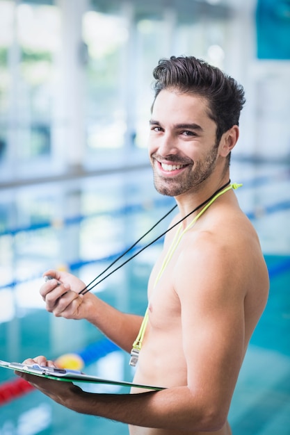 Gut aussehender Mann, der Klemmbrett und Stoppuhr am Pool hält