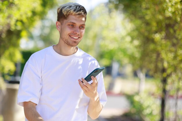 Gut aussehender Mann, der sein Telefon lächelt und hält