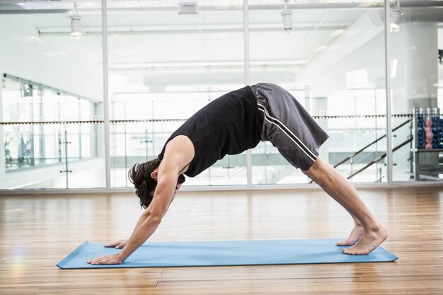 Gut aussehender Mann, der Yoga auf Matte im Studio tut