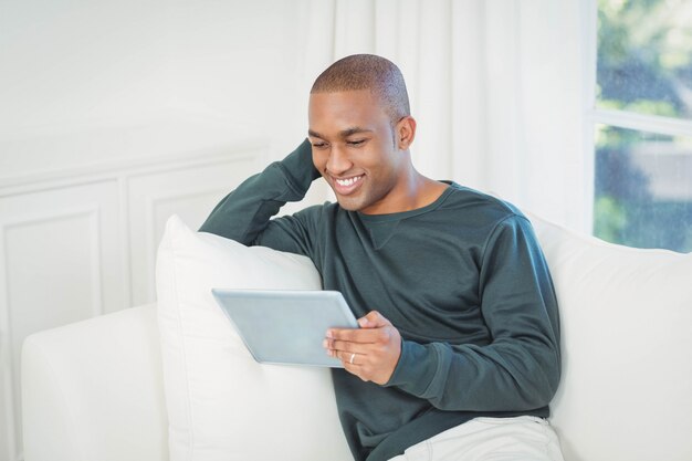 Gut aussehender Mann, der zu Hause Laptop auf dem Sofa verwendet