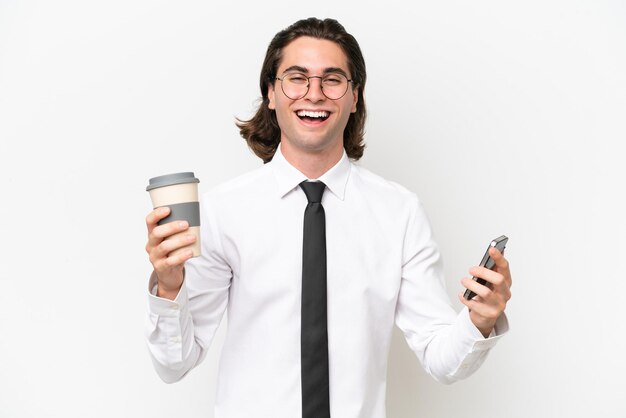 Gut aussehender Mann des Geschäfts lokalisiert auf weißem Hintergrund, der Kaffee zum Mitnehmen und ein Handy hält