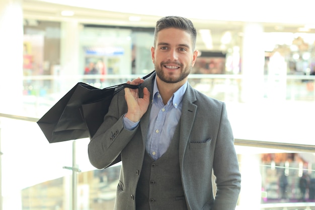 Foto gut aussehender mann im anzug mit einkaufstüten.